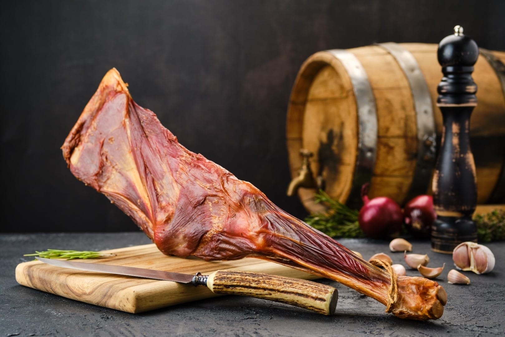 Slices of air dried lamb meat on a wooden cutting board, showcasing its texture and rich color.