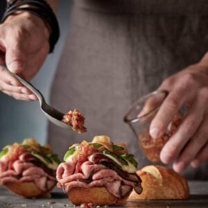 A chef skillfully assembling a sandwich with fresh ingredients, highlighting Boar's Head training services Jacksonville FL.