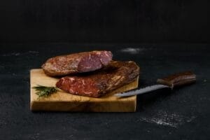 Smoked beef striploin meat displayed on a wooden cutting board, showcasing its rich color and texture.