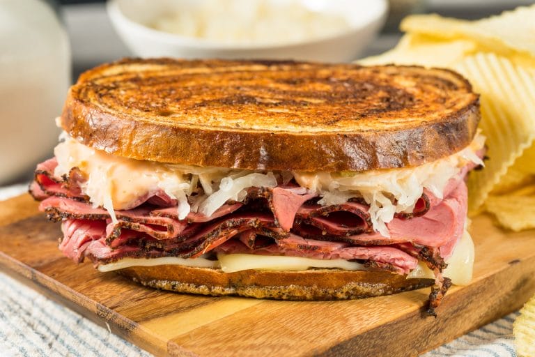 Ruben sandwich with pastrami, swiss cheese and sauerkraut with potato chips on the side