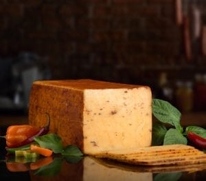 Boar's Head Bold Chipotle Gouda cheese block on a wooden board, offered by a cheese supplier Jacksonville.