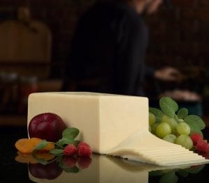 cheese supplier Jacksonville - Boar's Head Vermont White Cheddar cheese block on a wooden board, offered by a cheese supplier